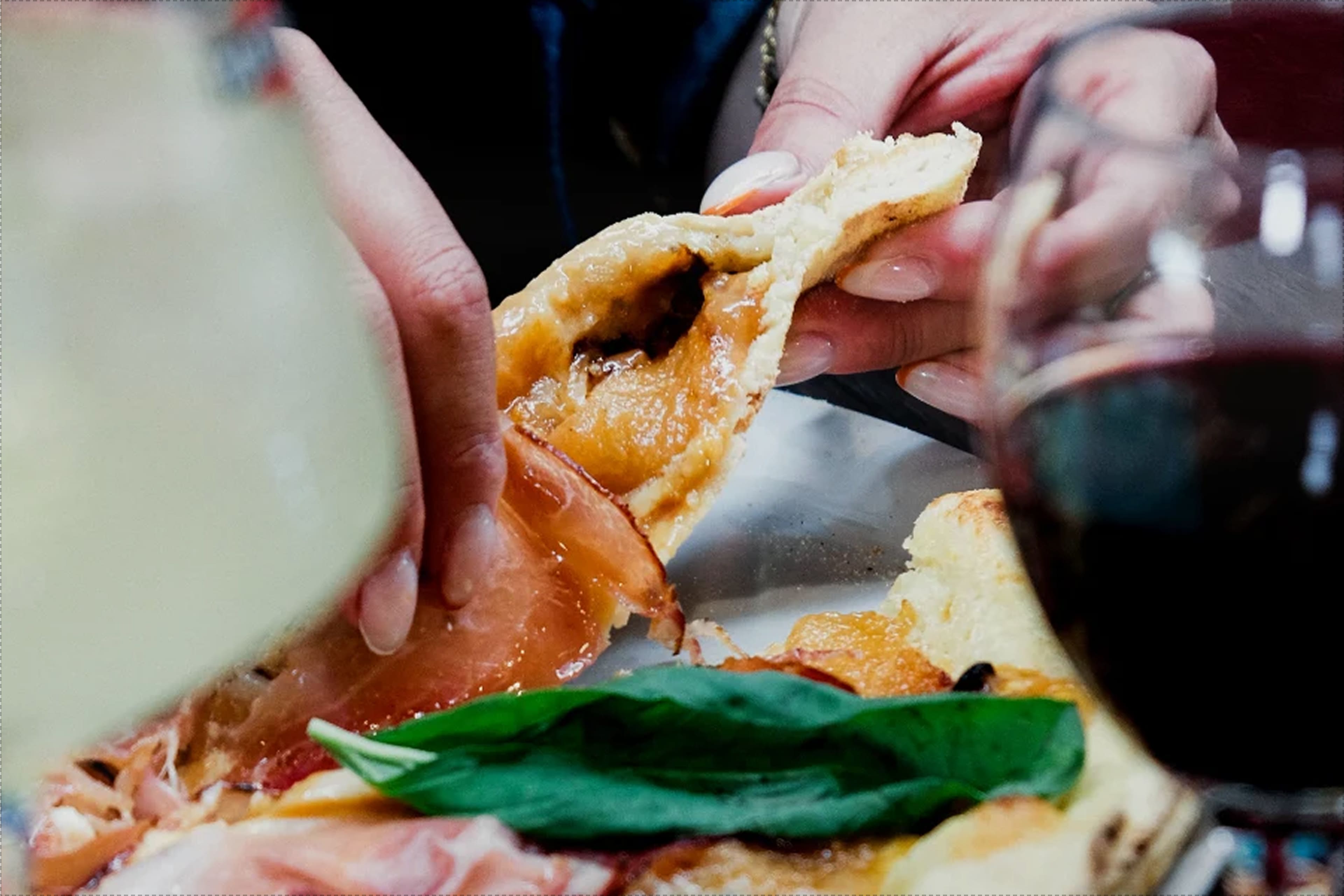Pizza partagée entre convives, verres de vin sur la table