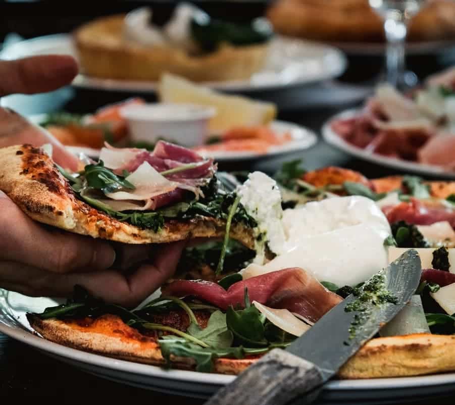 Pizza garnie de burrata, roquette, prosciutto et parmesan