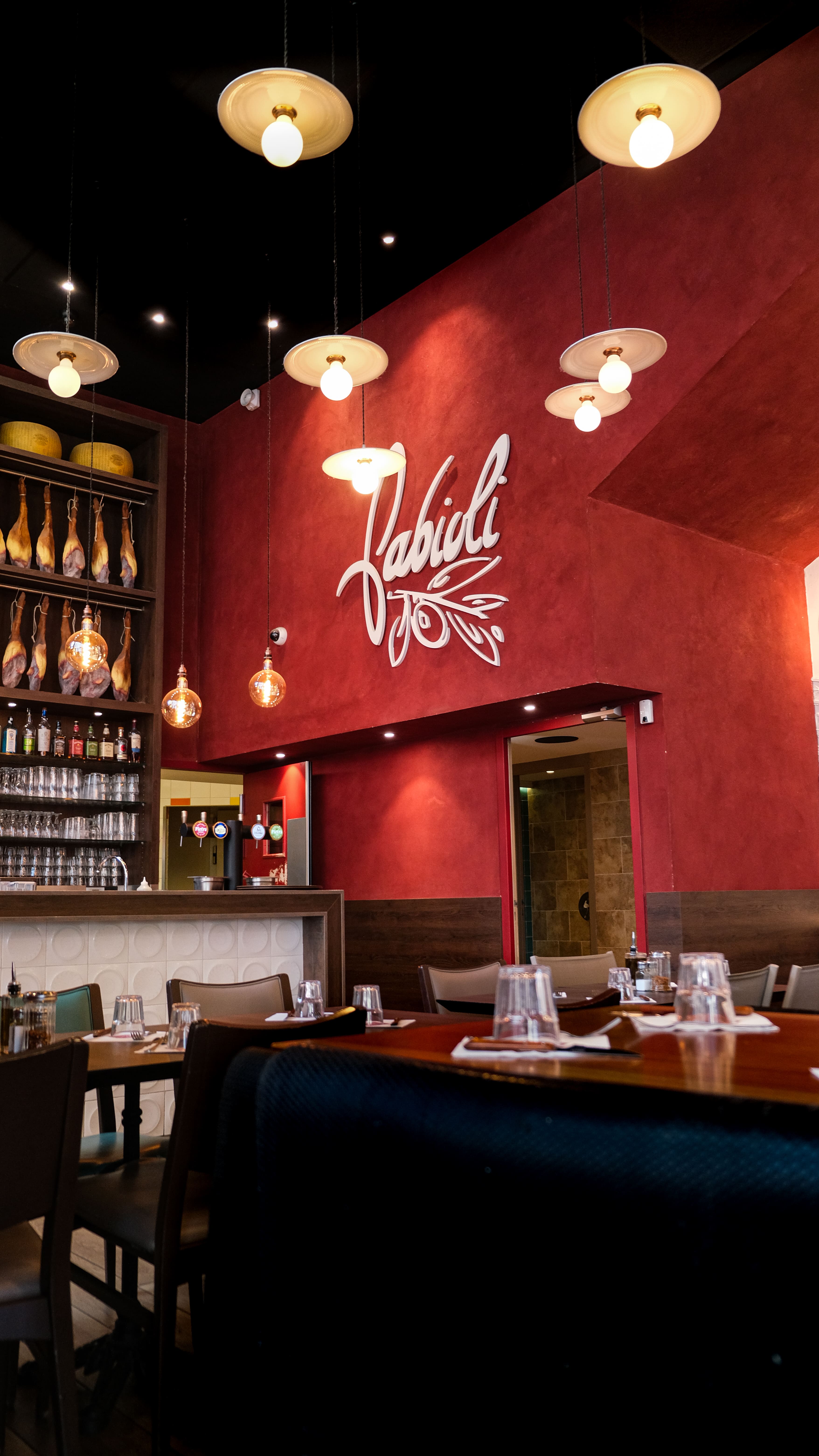 Salle du Restaurant Fabioli aux murs rouges et jambons suspendus
